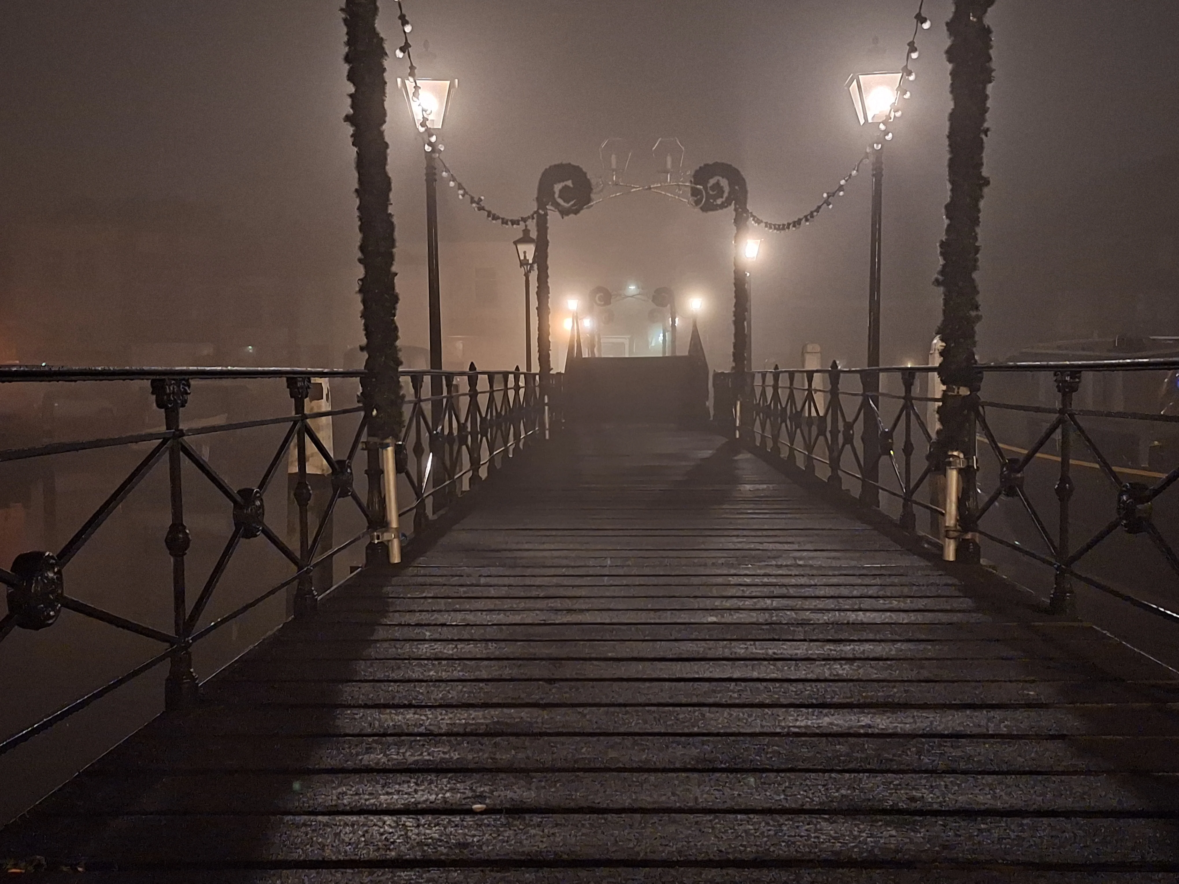 Illuminated bridge disappearing into fog